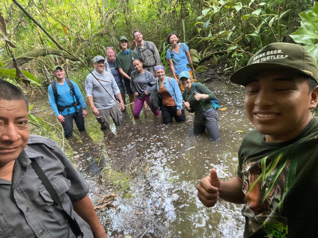 Group photo at NAFTRG survey group of researchers standing knee deep in water in the forest